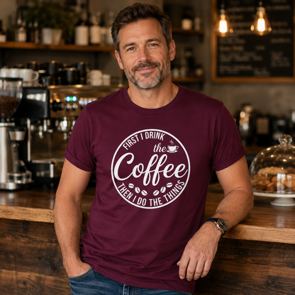 Man wearing First I Drink The Coffee maroon t-shirt in coffee shop