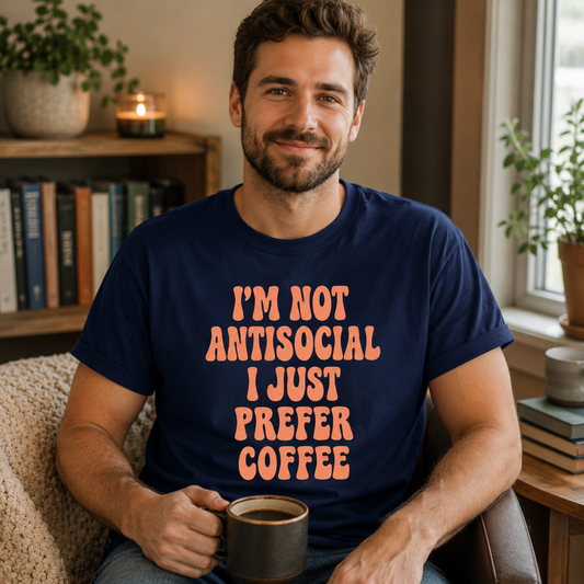 Man wearing I'm Not Antisocial I Just Prefer Coffee navy t-shirt in cozy reading corner